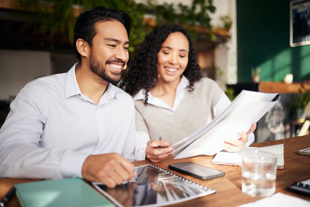 Two employees smiling at results listed on paperwork.
