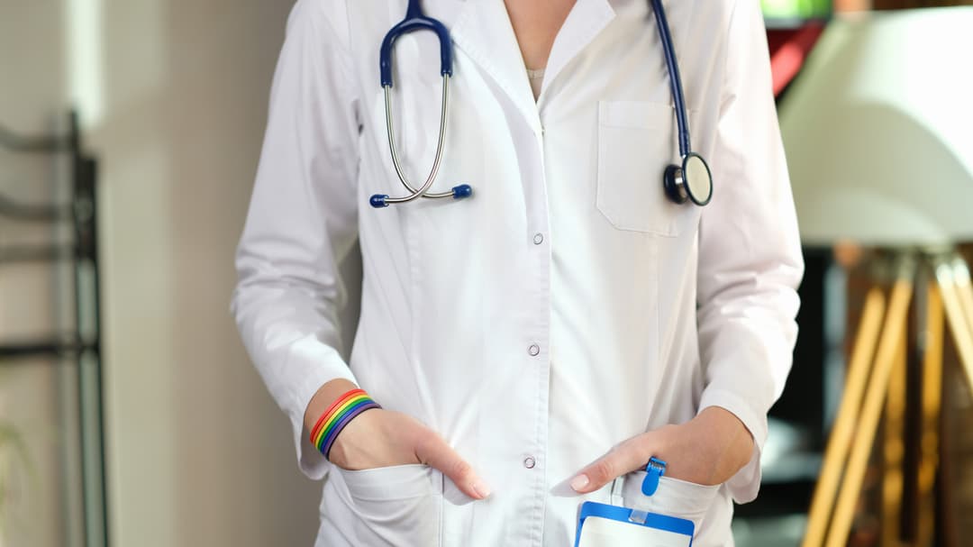 Female doctor with LGBT bracelet puts hands into pockets