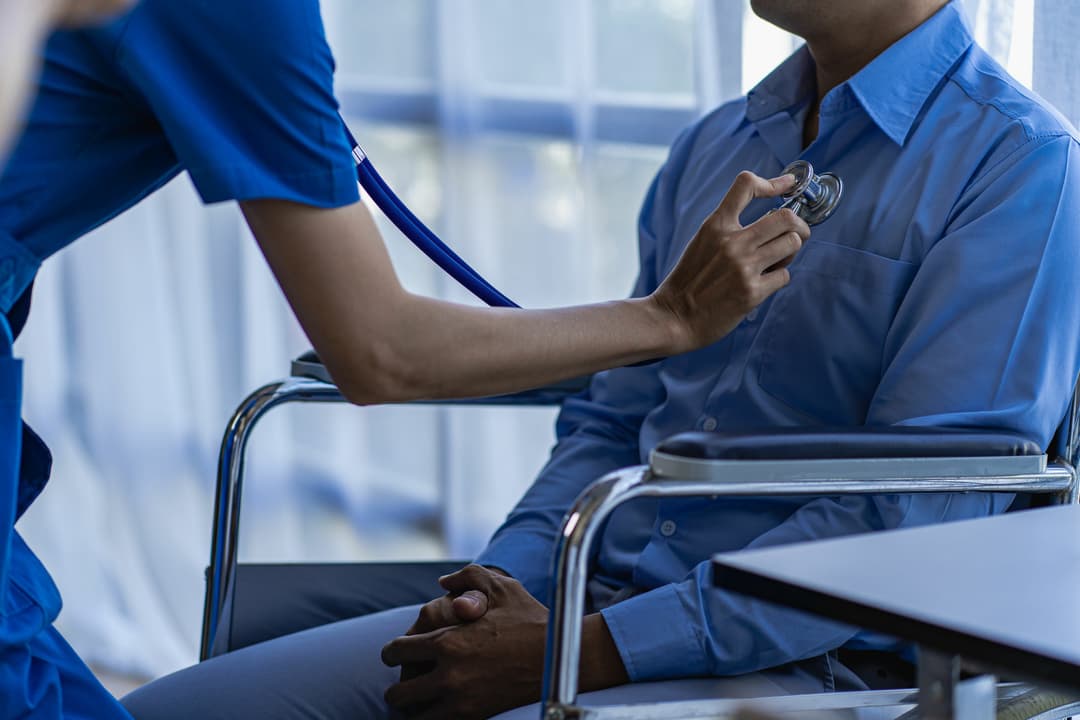 Nurse using stethoscope to check a patient's heart beat