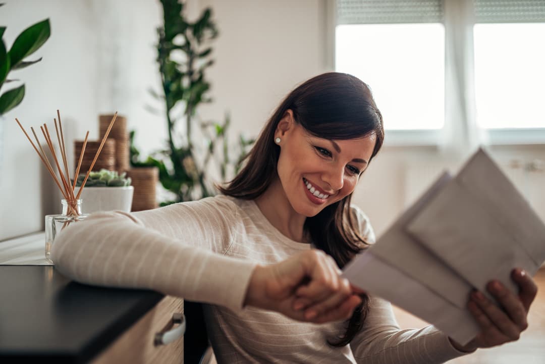 Woman smiling reviewing paper bill