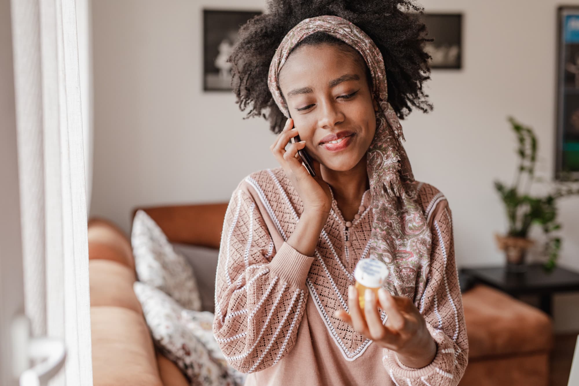 young black woman smiling looking at prescription pill bottle after having prescription filled through CapitalRX on the curative health plan
