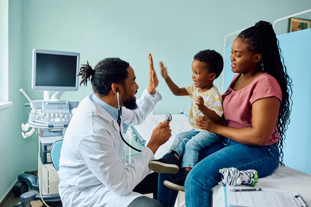 Happy boy giving high five to his pediatrician after medical examination at doctor's office