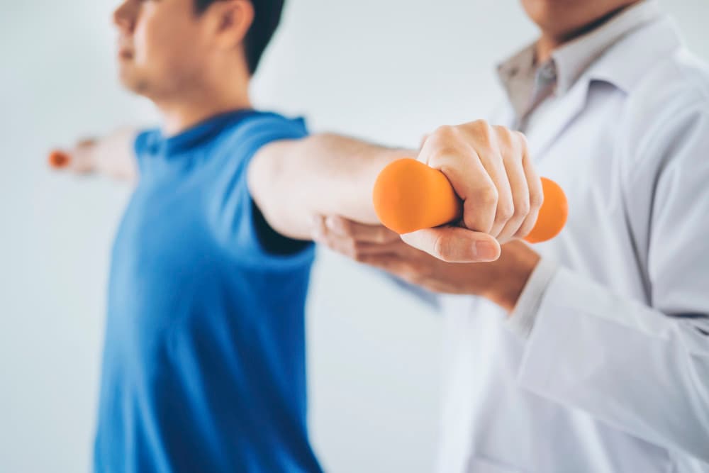 physical therapist giving a patient an exercise with an organce dumbbell