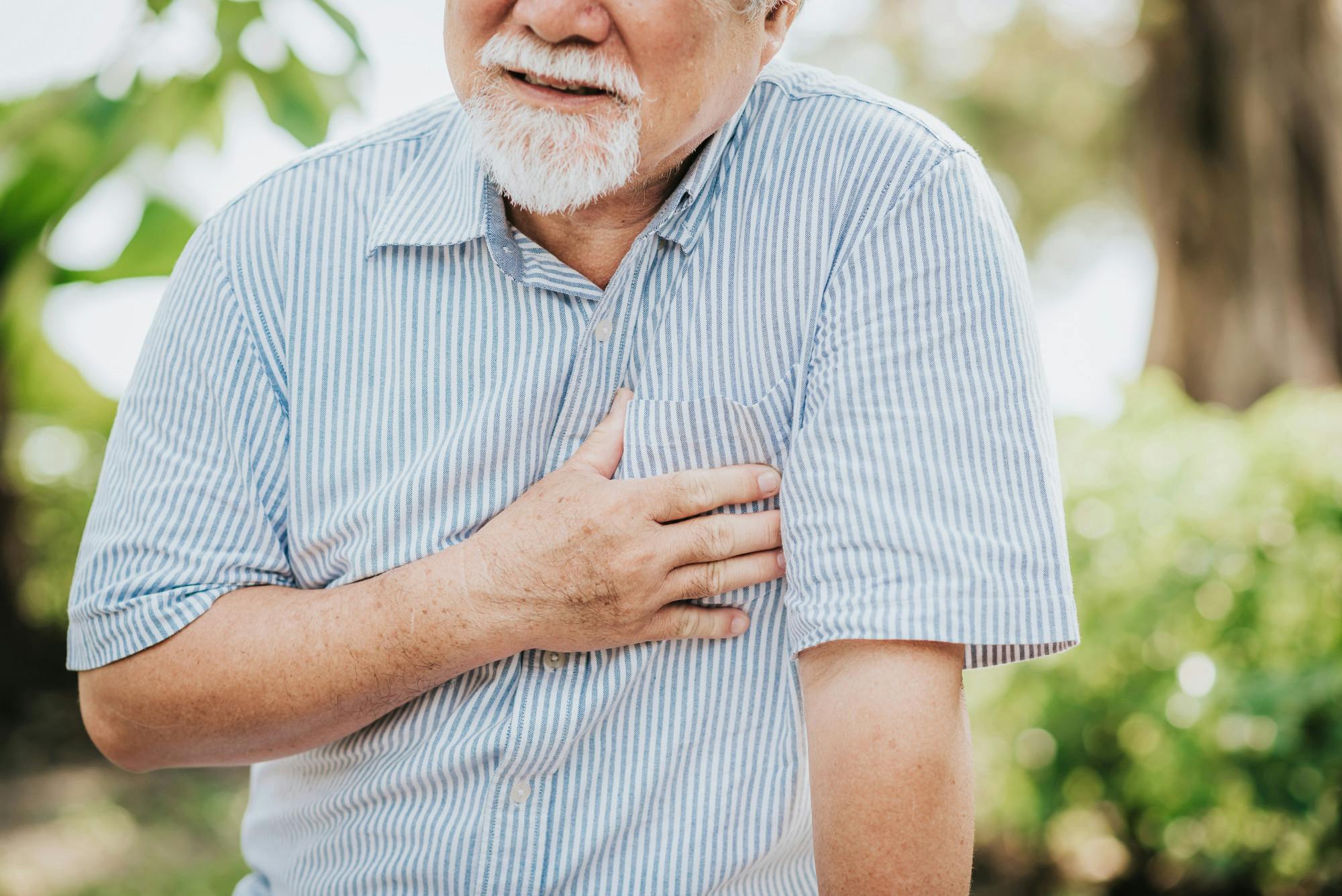 Man with white beard clutching his chest with chest pain