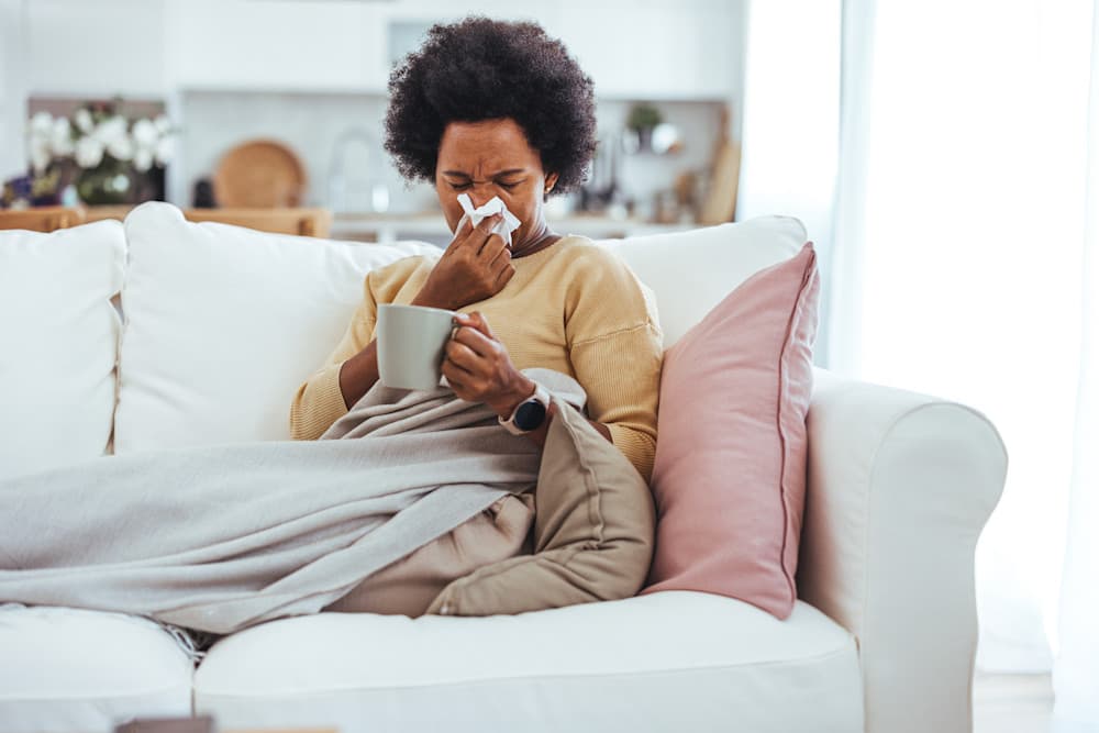 Worried African American woman sitting at home while being sick