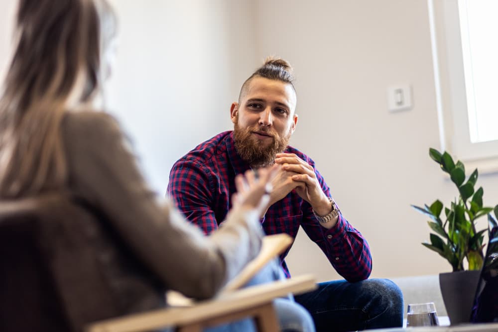 Female psychologist talking to young man during session
