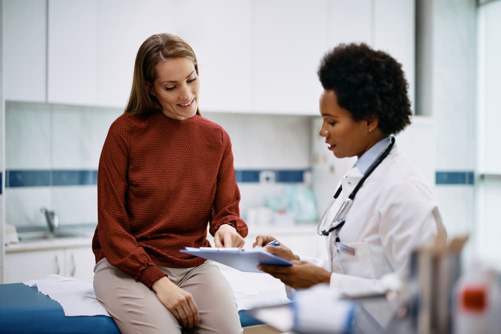 Happy woman going through her medical data with black female doctor at the clinic