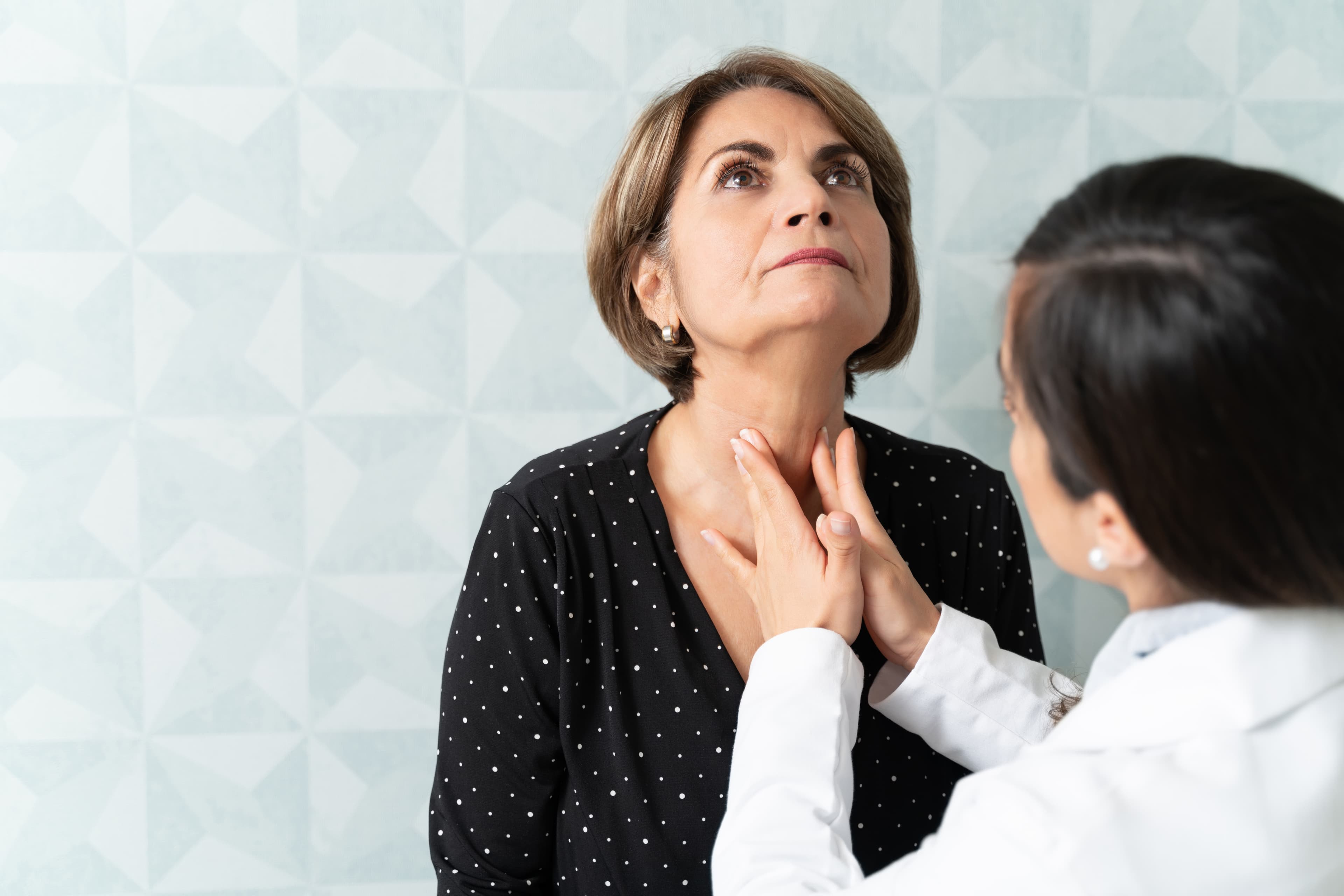 Doctor Examining Senior Patient's thyroid In Clinic