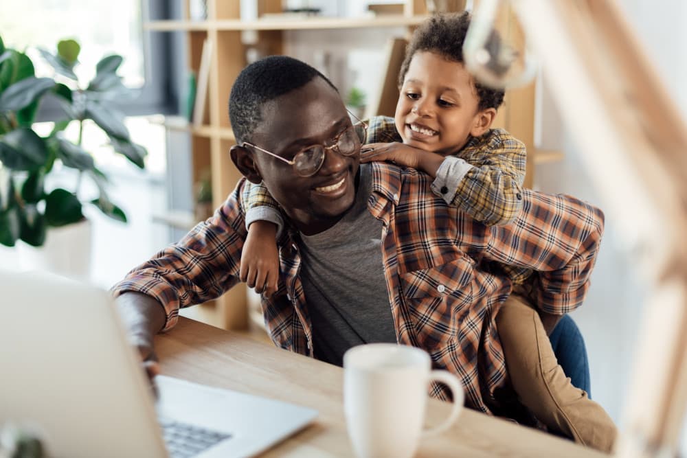 Son and father converse at kitchen table while father works