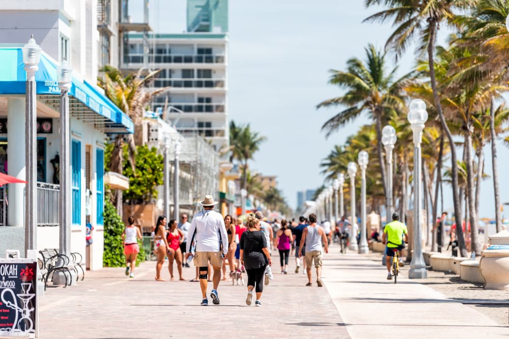 Beach boardwalk in Florida Miami Broward county with sunny day and people walking on promenade coast by cafe and restaurants exercising