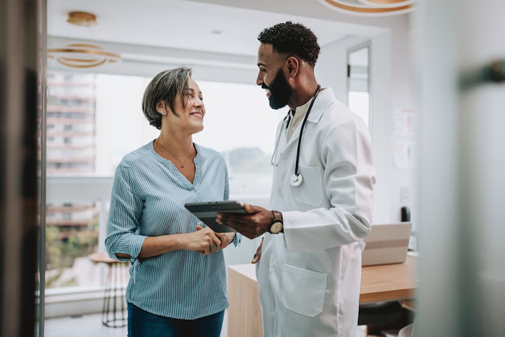 Doctor talking to patient holding digital tablet