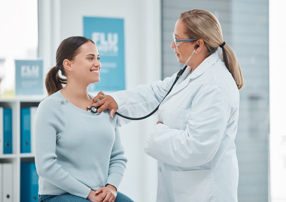 doctor examining a patient with a stethoscope during a consultation in a clinic