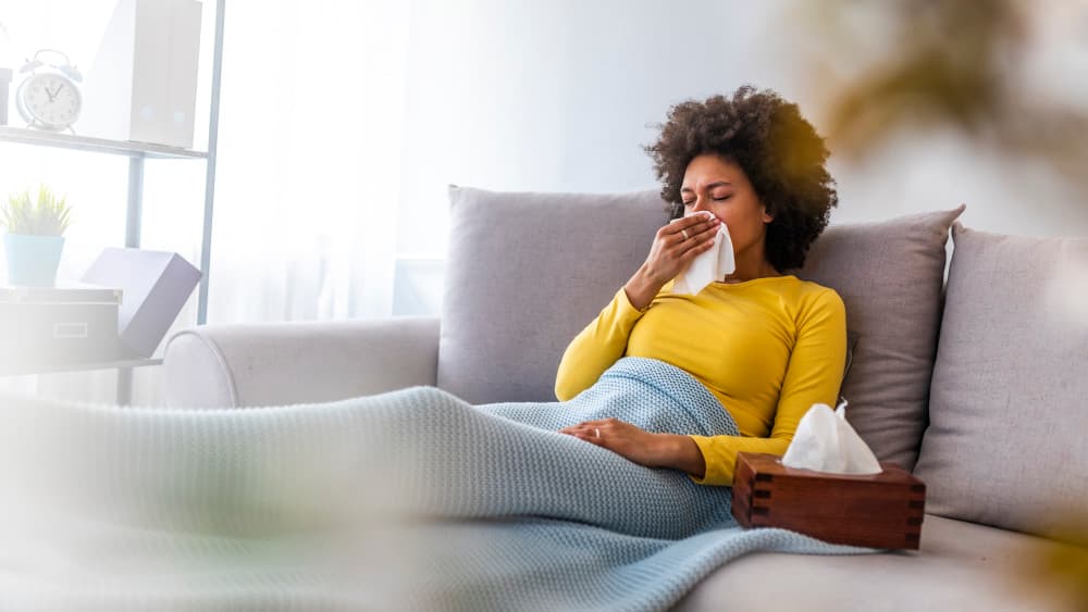 Woman sneezing in a tissue in the living room
