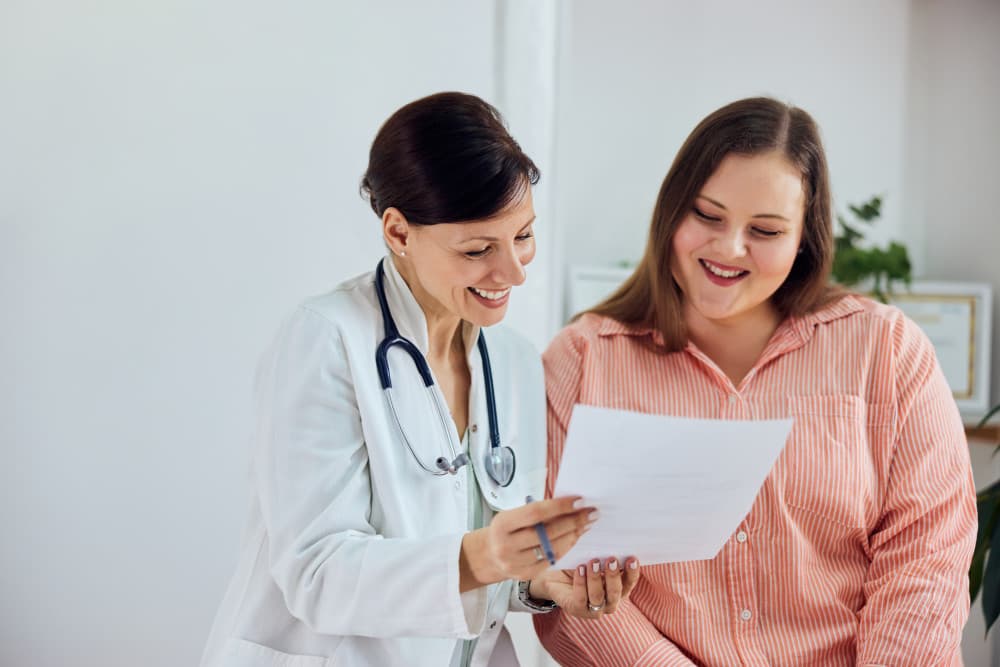A smiling female nutritionist showing good progress results to a happy overweight patient.