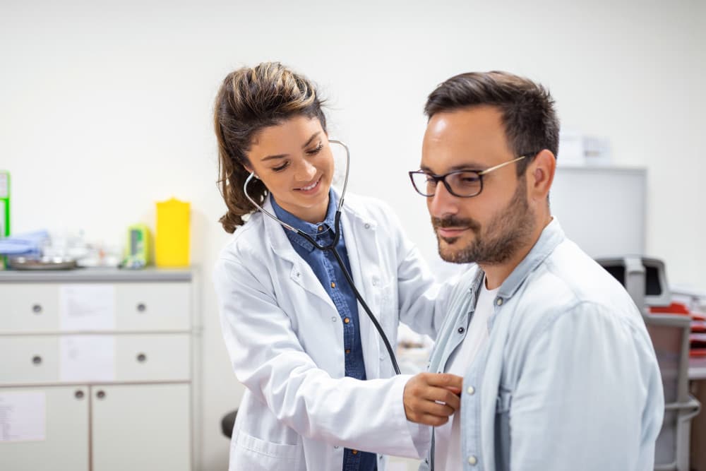 Young doctor is using a stethoscope listen to the heartbeat of the patient.