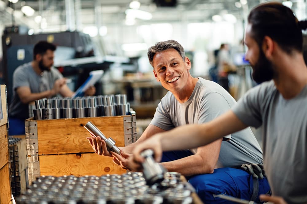 Happy employees talking while working together at steel factory